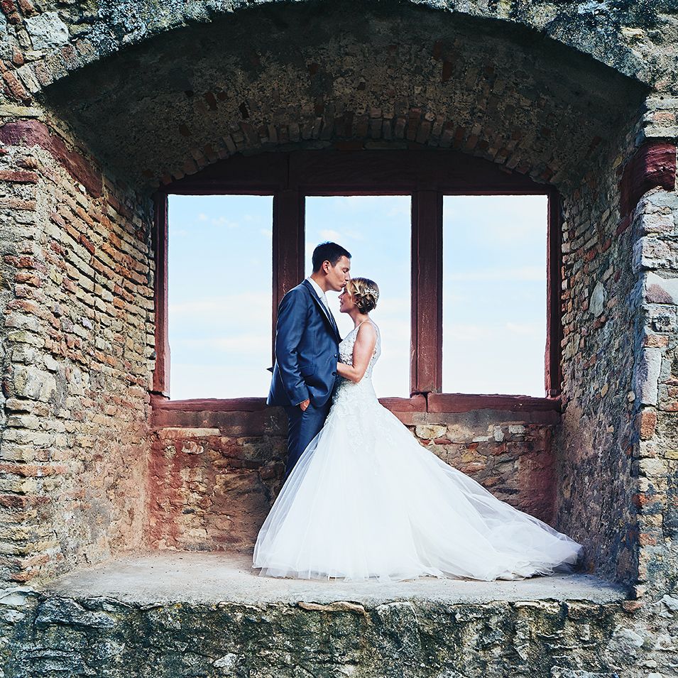 Romantischer Kuss des Brautpaars am Fenster einer Ruine