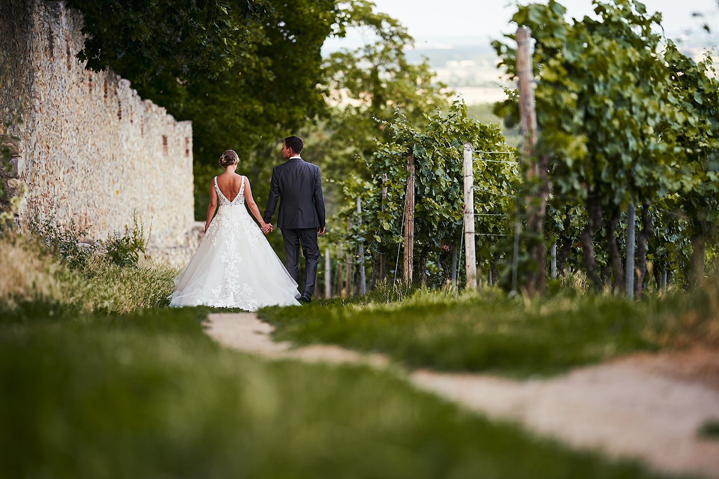 Brautpaar läuft Hand in Hand auf Feldweg in der Natur