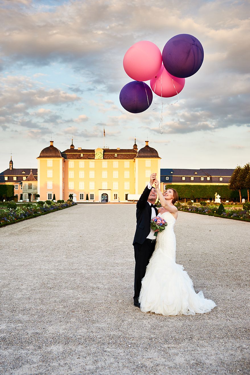 Brautpaar mit Luftballons vor romantischer Schlosskulisse