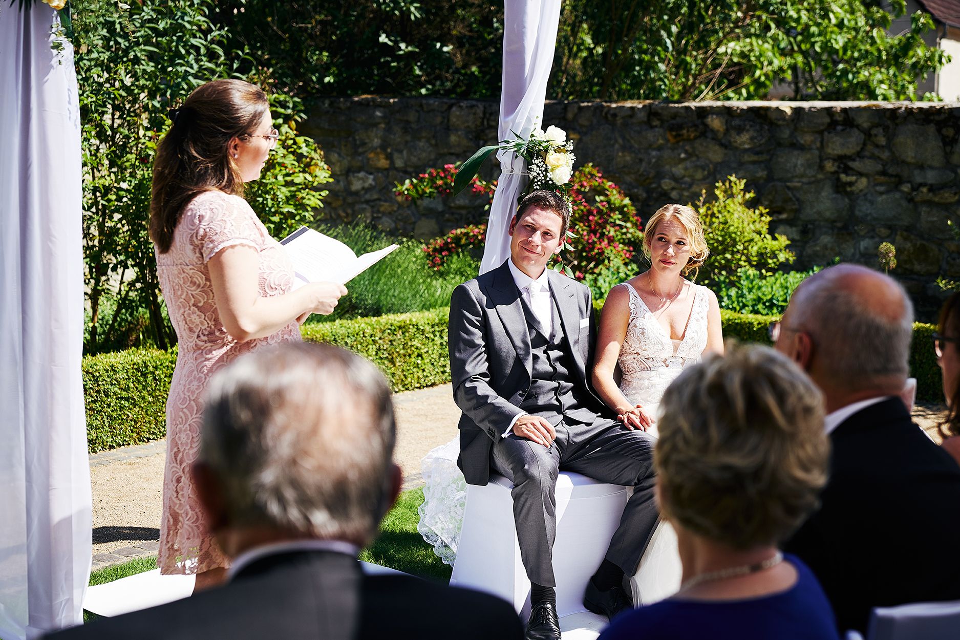 Freie Trauung im Garten mit sitzendem Brautpaar bei Zeremonie